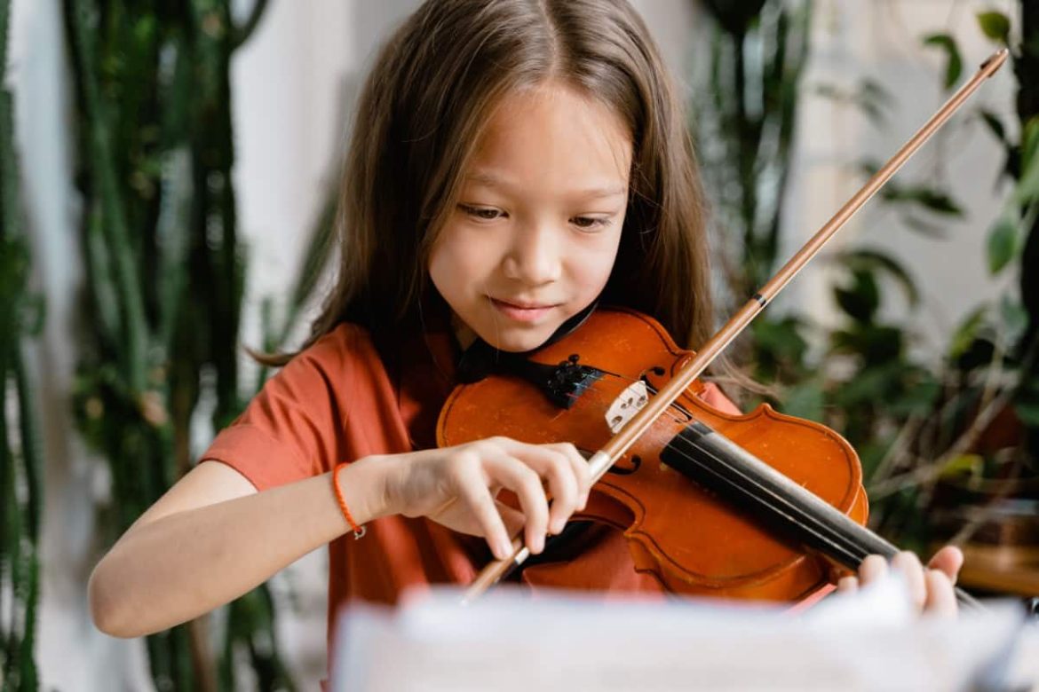 Une jeune fille attentive lit une partition pendant son cours de violon à la maison.