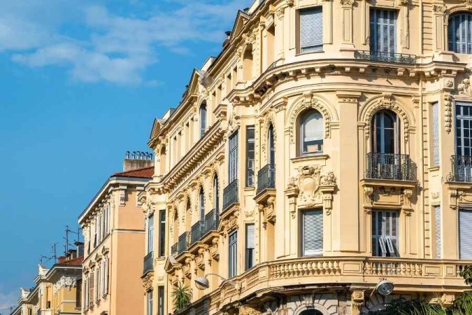 Façade d'angle haussmannienne ensoleillée à Nice, typique de l'architecture du centre d'affaires.