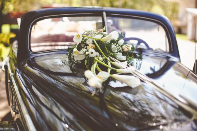 Capot d'une voiture ancienne noire orné d'un bouquet floral pour savoir quelle voiture choisir pour son mariage.